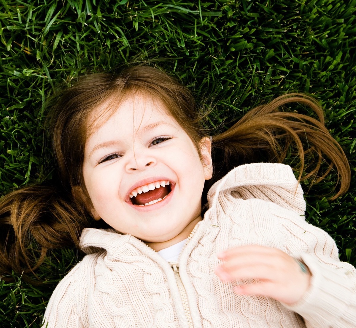 A young child laughing while lying in the grass